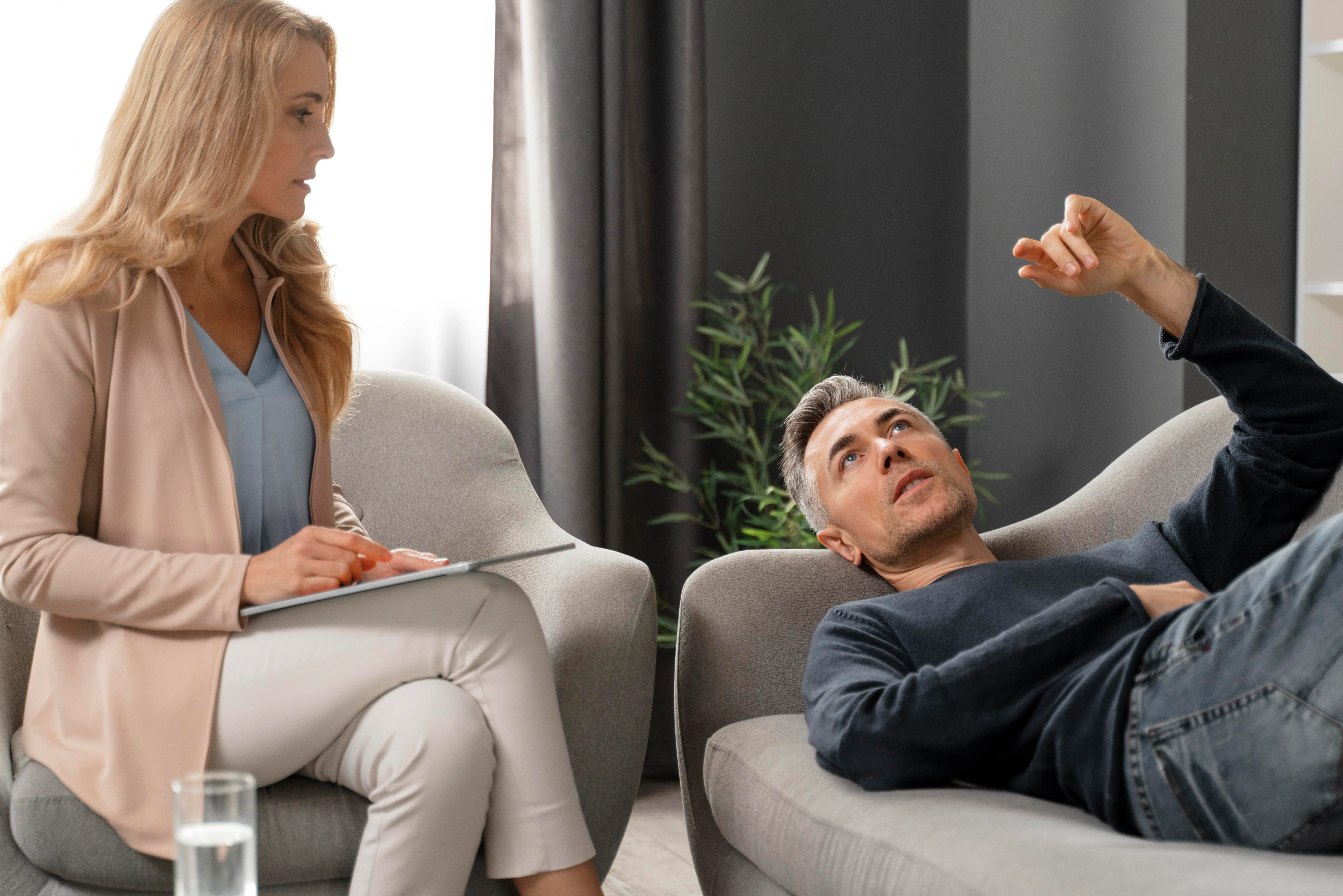 Patient relaxing on a therapy couch while counselor listens nearby